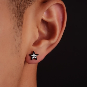 Close-up of black star earring with white geometric pattern on model's ear
