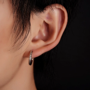 Detail of silver textured hoop earring on ear with intricate engraved patterns