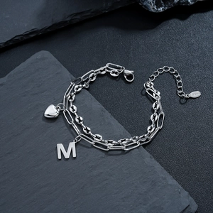 Dettaglio del bracciale a doppio strato in acciaio argento con ciondoli a cuore e M