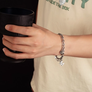 Dettaglio del bracciale a doppia catena in argento con ciondoli a cuore e lettera M