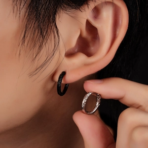 Detailed view of silver and black hoop earrings with intricate vintage engraved patterns