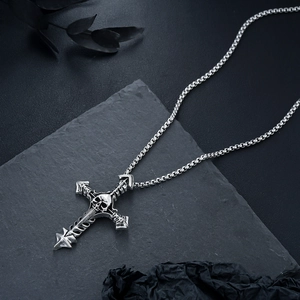 Macro shot of gothic cross pendant featuring skull relief on retro square pearl chain
