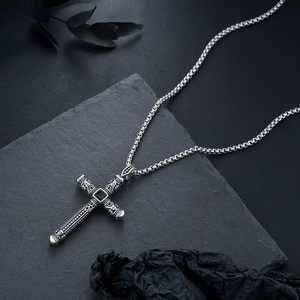 Vue macro du pendentif croix vintage avec pierre noire et textures métalliques gravées