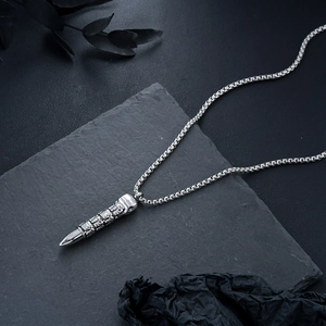Macro view of silver bullet pendant with skull relief on a heavy box chain link