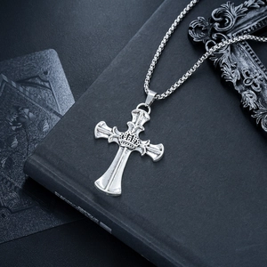 Dettaglio macro di una collana a croce argento vintage con corona su libro nero