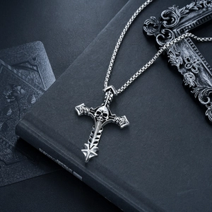 Macro view of vintage gothic silver skull cross pendant on a black book surface