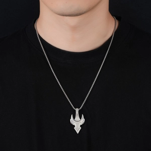 Close-up of a silver trident pendant on a chain worn over a black t-shirt