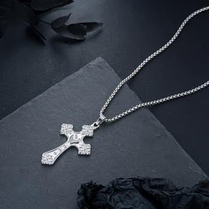 Détail du collier croix argenté avec motif cœur sur un fond de pierre sombre