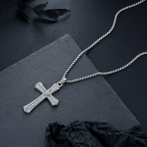 Vue détaillée du pendentif croix argenté serti de cristaux sur pierre sombre