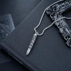 Macro detail of gothic skull bullet pendant on vintage silver box chain necklace