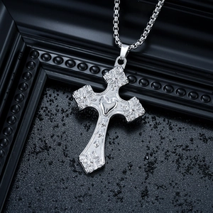 Détail du pendentif croix en argent antique avec gravures florales et centre en cœur