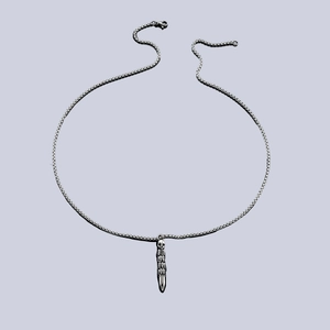 Macro detail of bullet pendant with skull relief on vintage silver chain necklace