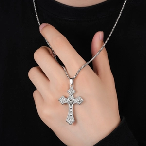 Vue détaillée du pendentif croix argentée avec cœur et relief baroque sur chaîne maille