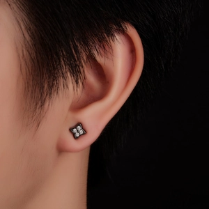 Macro shot of stylish black four-pointed star stud earring with clear zircon crystals