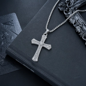 Vue détaillée du collier pendentif croix argenté avec strass brillants sur fond sombre