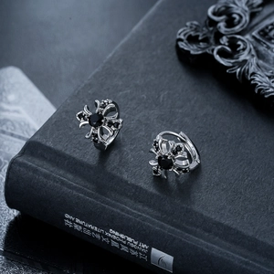 Close-up of gothic cross earrings with black zircon stones and hollow floral design
