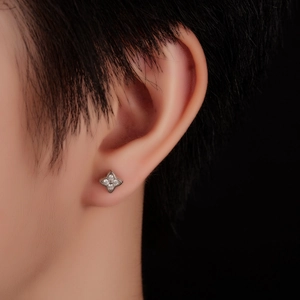 Close-up of a silver clover stud earring with sparkling zircons worn on the ear