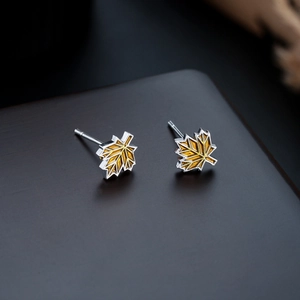 Macro detail of maple leaf stud earrings with silver metal and yellow geometric inlay