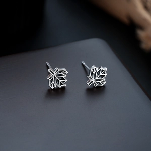 Macro shot of maple leaf stud earrings with detailed 925 silver geometric textures