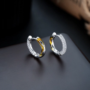 Macro shot of a gold and silver hoop earring with pavé zircon stones and lava texture