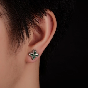Silver four-leaf clover stud earrings with green marquise stones worn on an ear