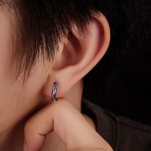 Silver men's hoop earring with blue enamel spiral design on male model's ear