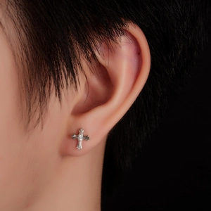Silver cross stud earring with zircon stone inlay shown on a model ear