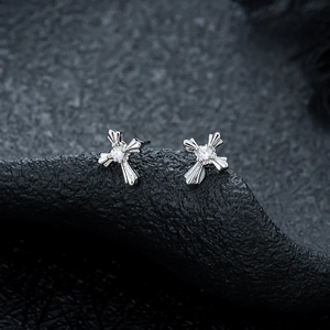 Detailed view of silver cross earrings with zircon center and radial stripe texture