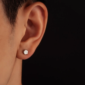 Macro detail of silver pentagon geometric stud earring with matte brushed metal texture