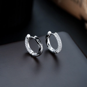 Detail of silver huggie earrings with pavé white zircons and black wave enamel finish