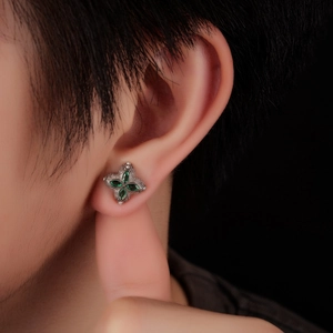 Elegant four-leaf clover stud earrings with green gemstones and pavé crystals on model