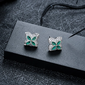 Macro shot of silver four-leaf clover earrings with green stones and pavé set crystals