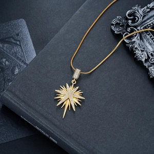 Macro shot of gold-plated starburst pendant with white cubic zirconia on snake chain