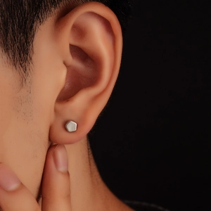 Minimalist matte silver hexagonal stud earring for men and women on dark background