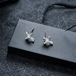 Detail view of silver cross stud earrings with sparkling cubic zirconia on black leather