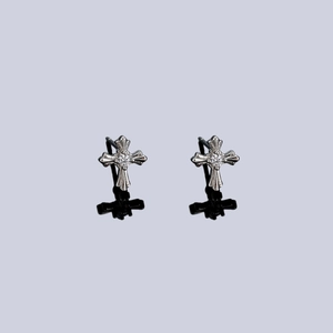Gothic style cross stud earrings with central zircon stone on a black mirror surface
