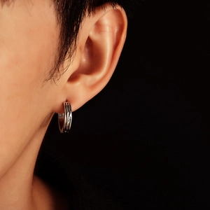 Close-up of men's silver hoop earring with engraved industrial texture on the earlobe