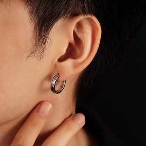 Minimalist silver steel hoop earring with engraved stripes on male model