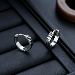 Macro shot of silver hoop earrings with unique flowing texture on black jewelry box