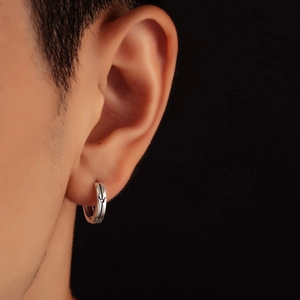 Dettaglio di un orecchino a cerchio d'argento con corona incisa in stile vintage