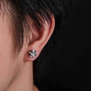 Detail of star-shaped stud earring with clear zircon and black metal plating finish