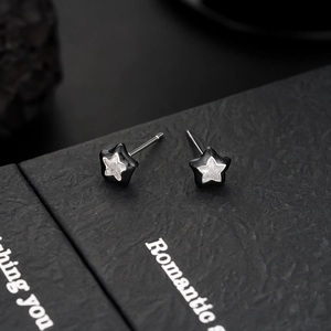 Macro shot of black star earrings with clear cubic zirconia on a leather jewelry box