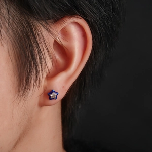 Star-shaped zircon earrings with blue enamel finish and silver center detail on model