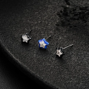 Macro shot of star-shaped stud earrings with zircon inlay on a dark stone background