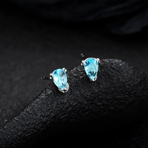 Macro shot of blue teardrop-shaped zircon earrings set in silver metal claws