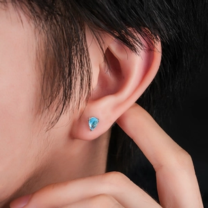 Close-up of pear-shaped blue zircon stud earrings on model ear with silver settings