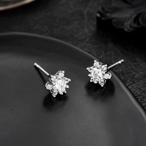 Macro shot of silver snowflake earrings with micro-pave zircons on a dark tray