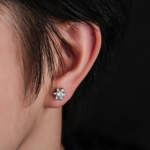 Micro-pave snowflake earrings with cubic zirconia on model against black background