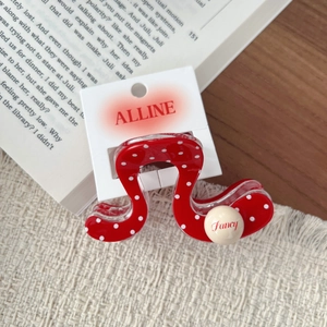 Detailed view of a red polka dot hair claw clip with a fancy bead on a brand card