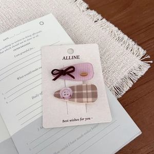 Close-up of vintage check pattern hair clip set with button and bow on display card